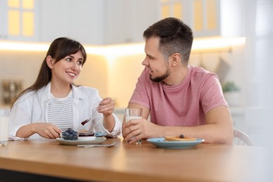 Happy couple having tasty breakfast at home