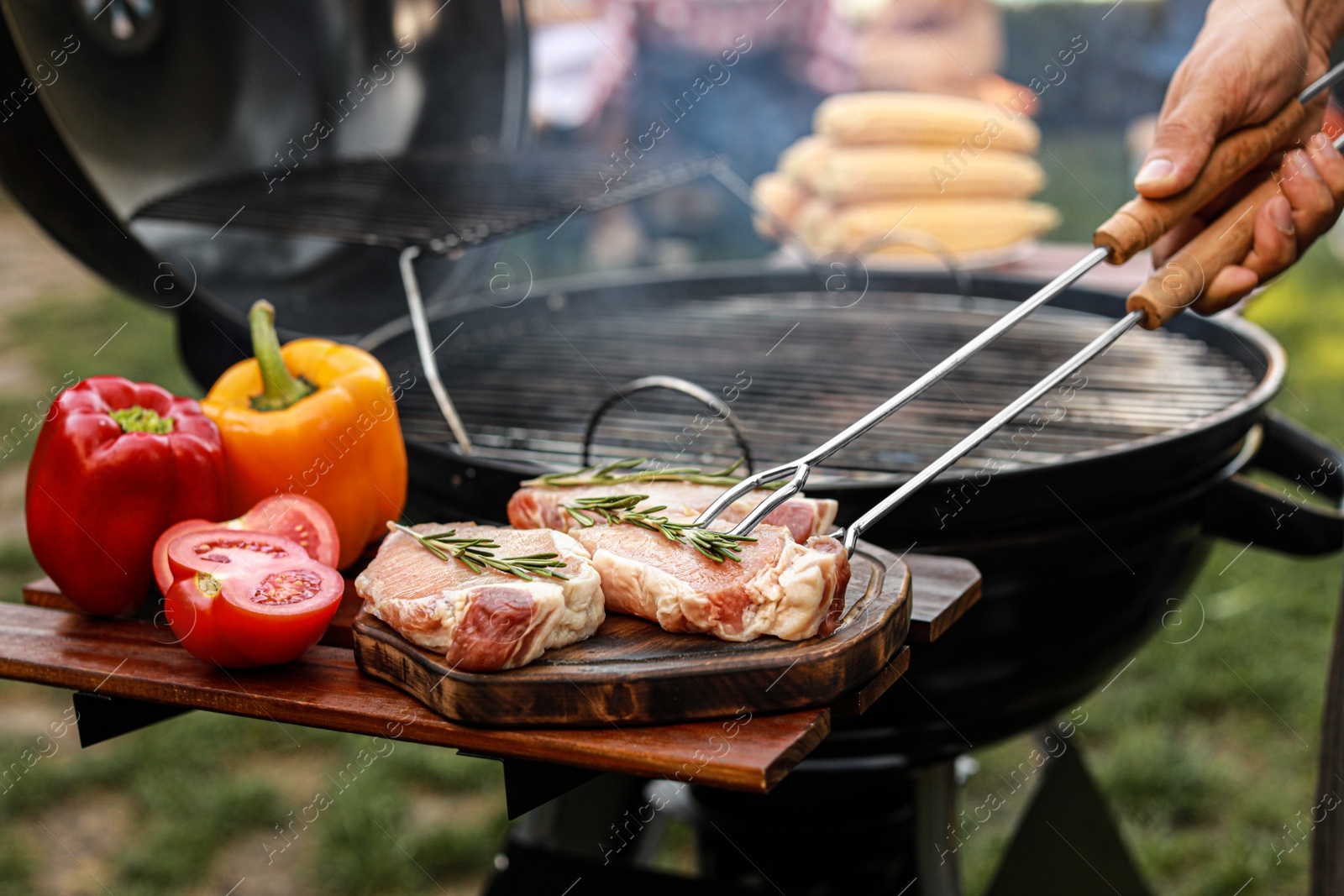 Photo of Man cooking on barbecue grill outdoors, closeup