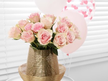 Photo of Beautiful bouquet of rose flowers in vase and air balloons in room, space for text. Happy birthday