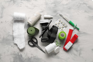 Photo of Tourniquet, medical cotton, scissors and pills on light grey table, flat lay