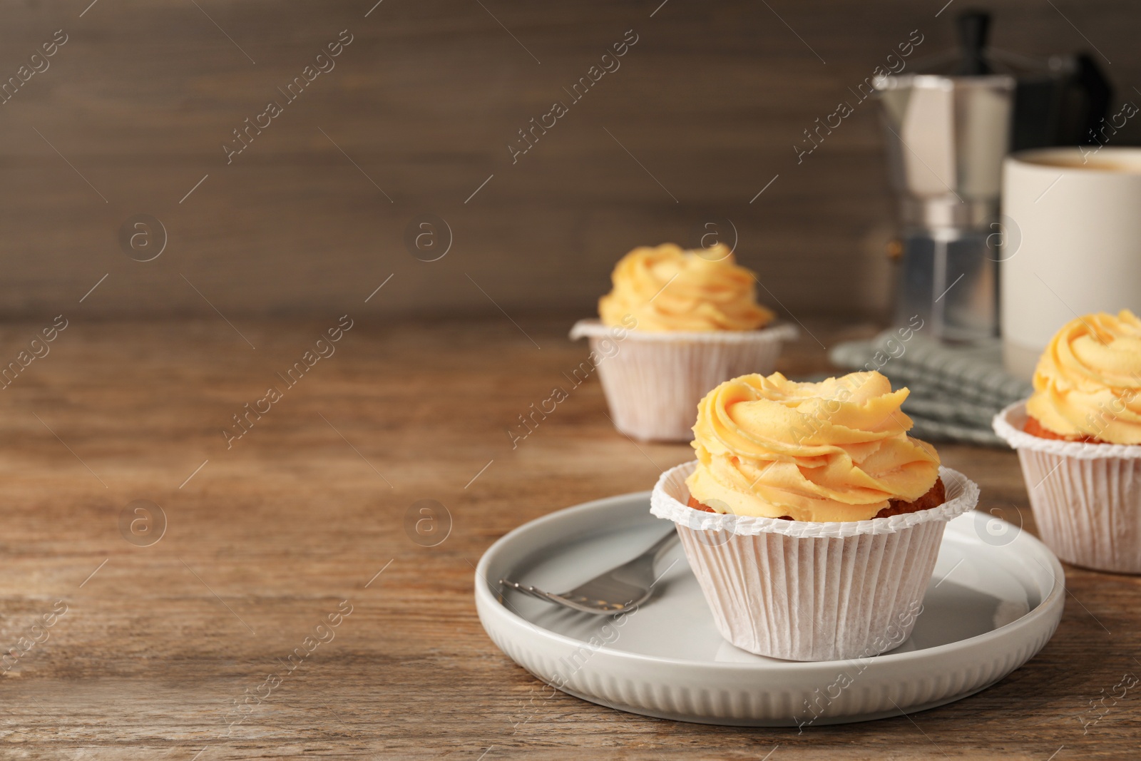 Photo of Tasty cupcakes with cream served on wooden table. Space for text