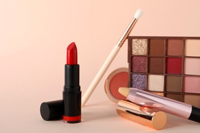 Photo of Beautiful red lipstick and cosmetic products on beige background