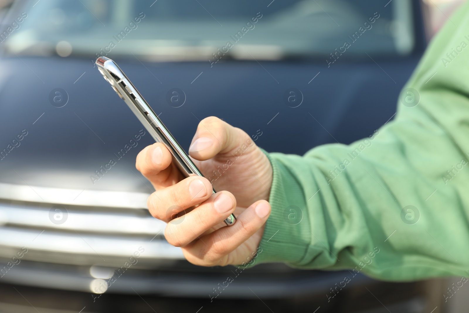 Photo of Man ordering taxi with smartphone on city street, closeup