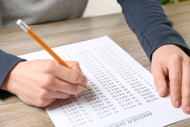 Photo of Student filling answer sheet at table, closeup