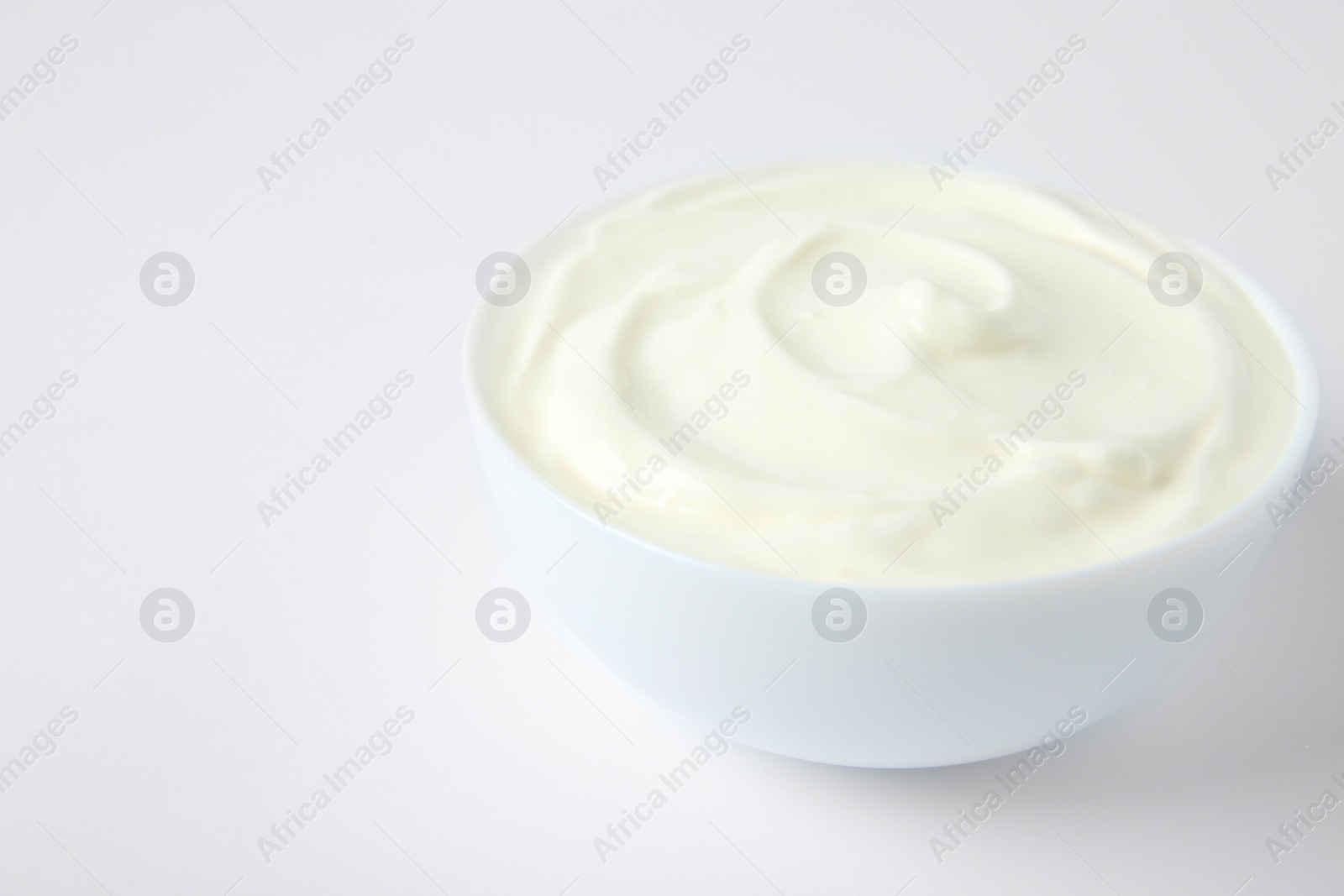 Photo of Bowl of fresh sour cream on white background