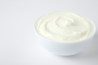 Bowl of fresh sour cream on white background