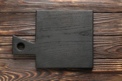 Black cutting board on wooden table, top view