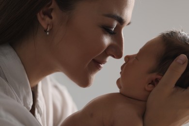 Photo of Mother holding her newborn baby on light grey background, closeup