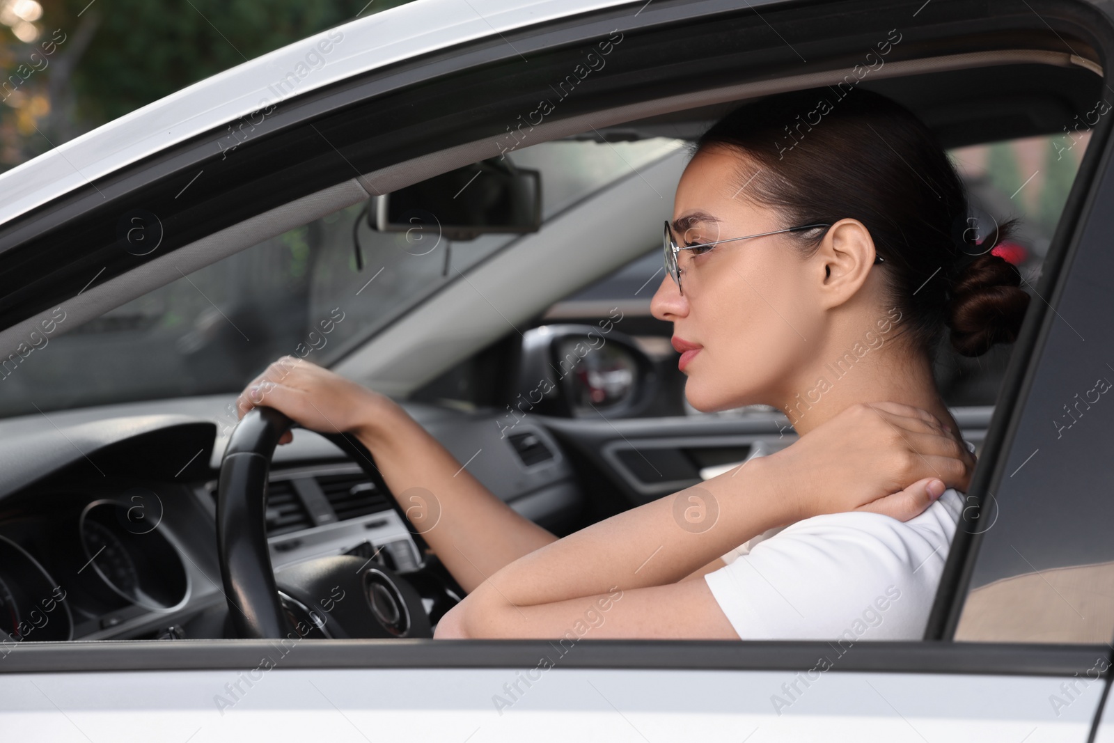 Photo of Young woman suffering from neck pain in her car