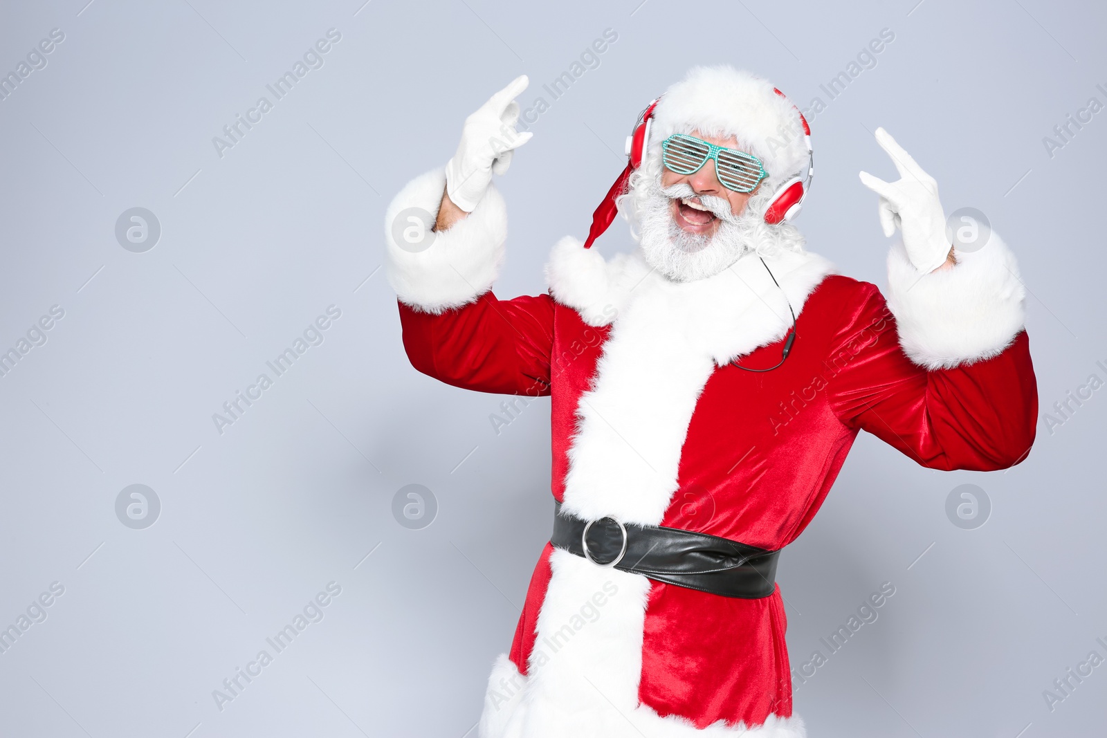 Photo of Santa Claus listening to Christmas music on color background