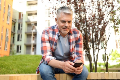 Photo of Handsome mature man using phone in park