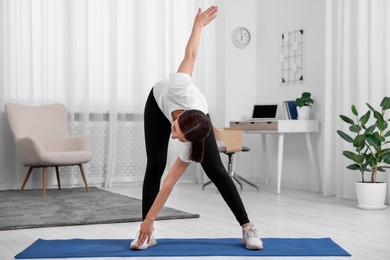 Photo of Woman doing morning exercise on mat at home
