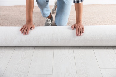 Photo of Man rolling out new carpet flooring indoors, closeup. Space for text