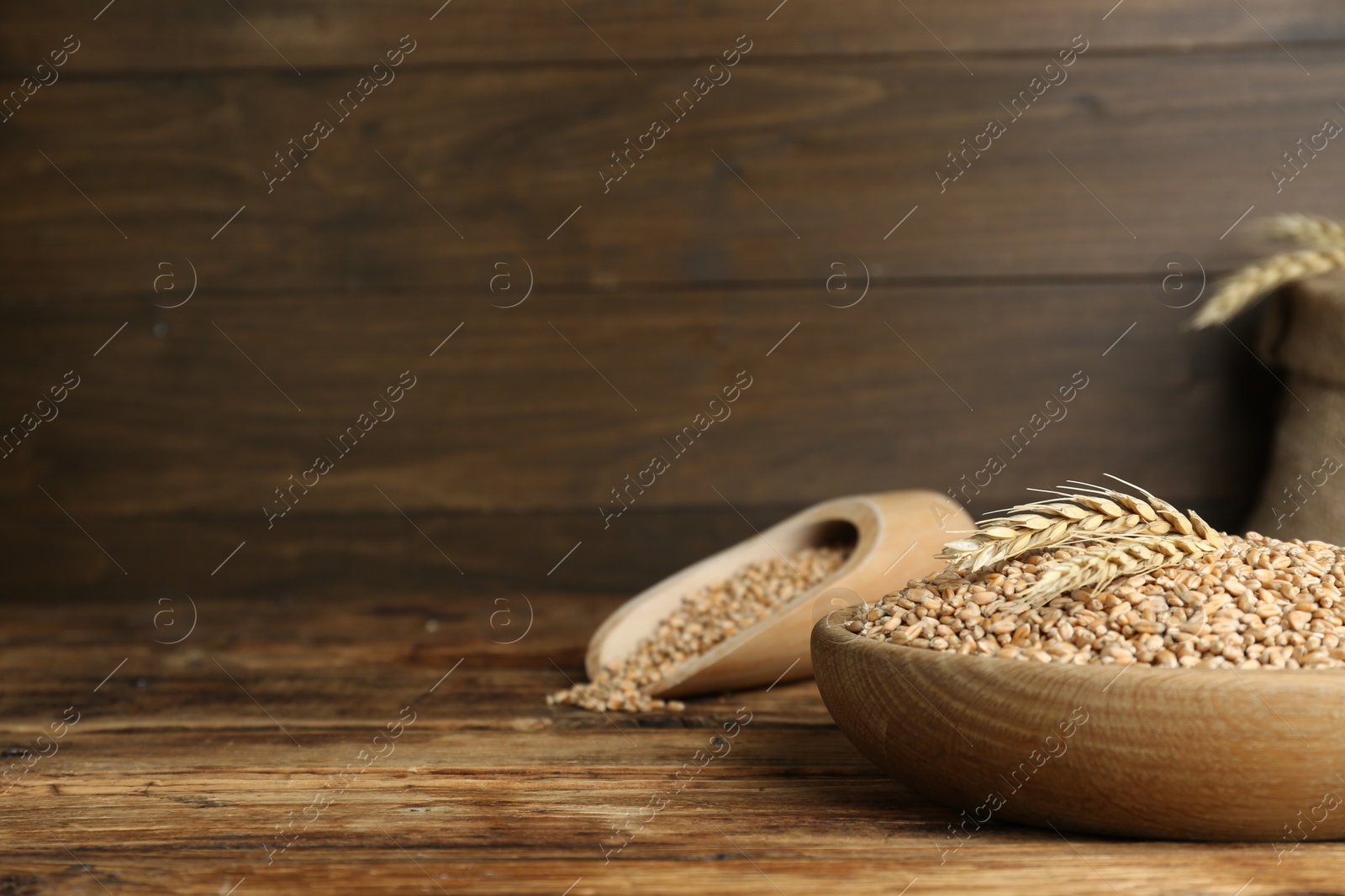 Photo of Bowl with wheat grains on wooden table