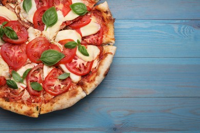 Photo of Delicious Caprese pizza on blue wooden table, top view. Space for text