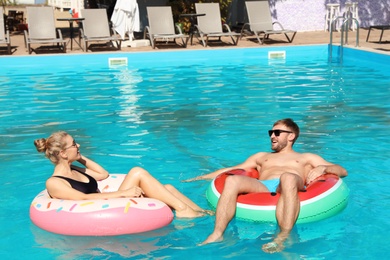 Photo of Happy young couple with inflatable rings in swimming pool