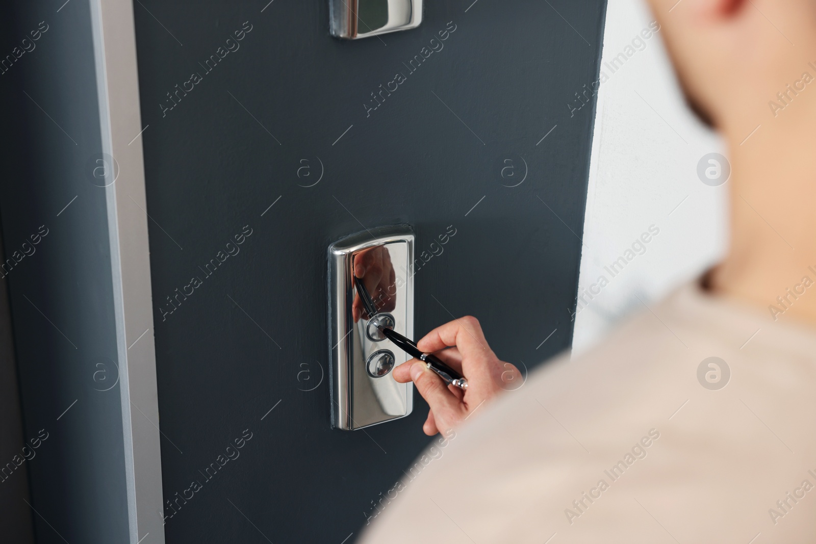 Photo of Man using pen to press elevator call button, closeup. Protective measure