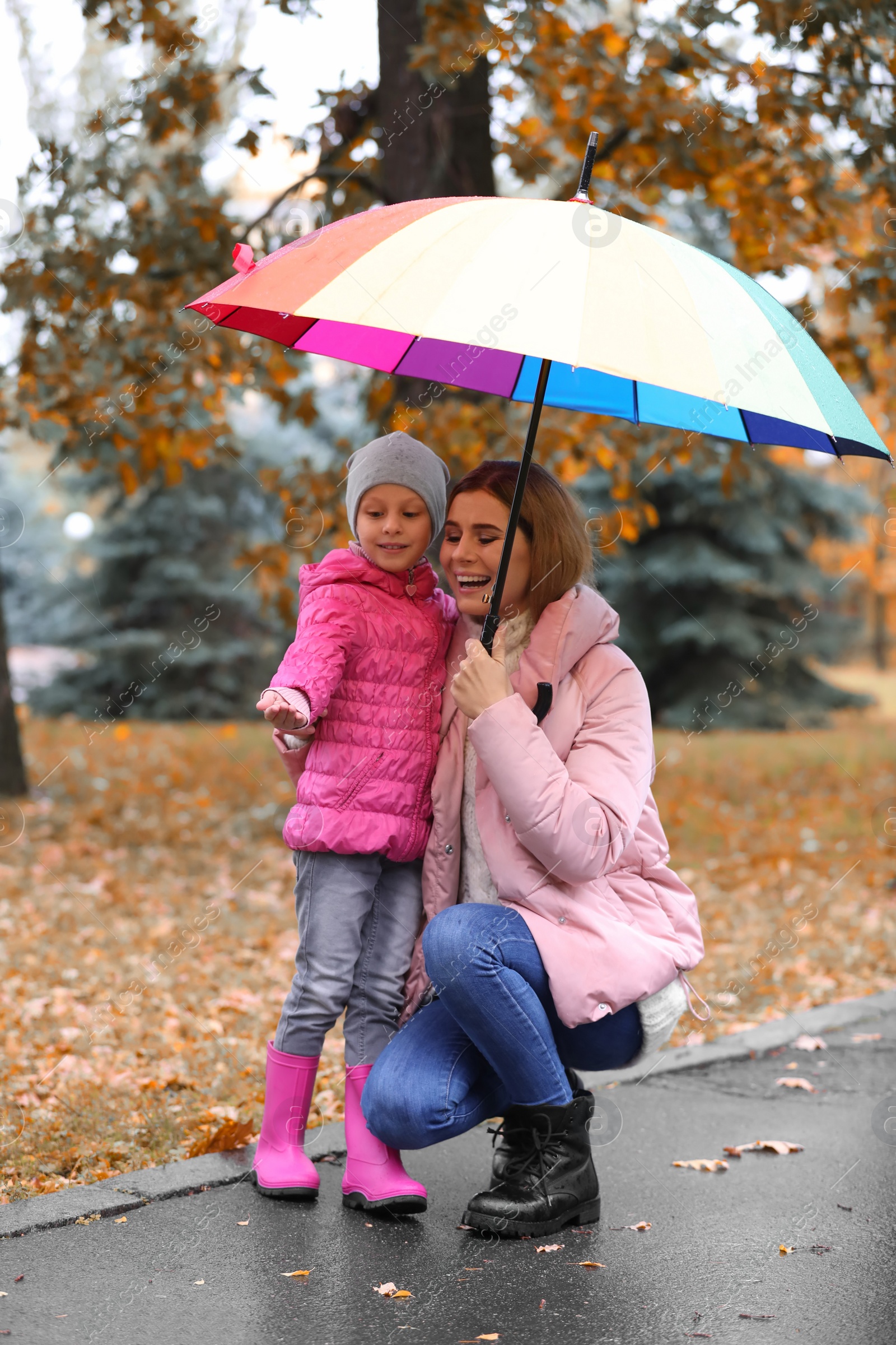 Photo of Mother and daughter with umbrella in autumn park on rainy day