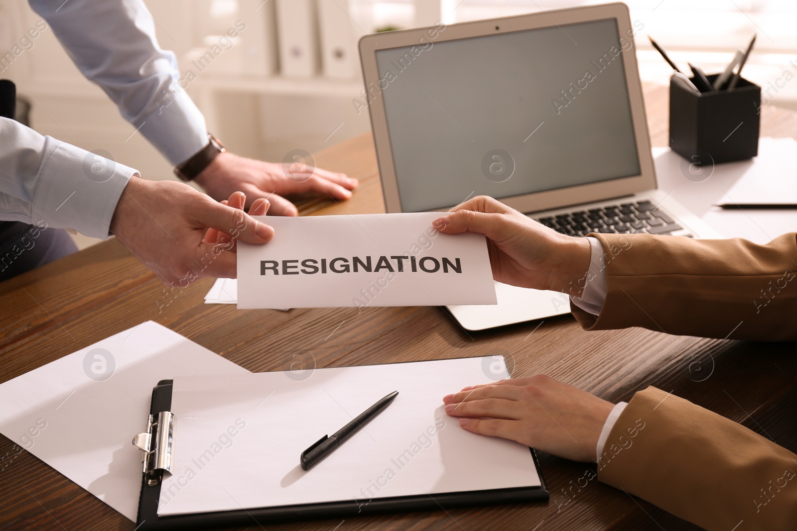 Photo of Employee giving resignation letter to boss in office, closeup