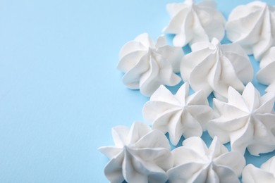 Photo of Tasty meringue cookies on light blue background, closeup. Space for text