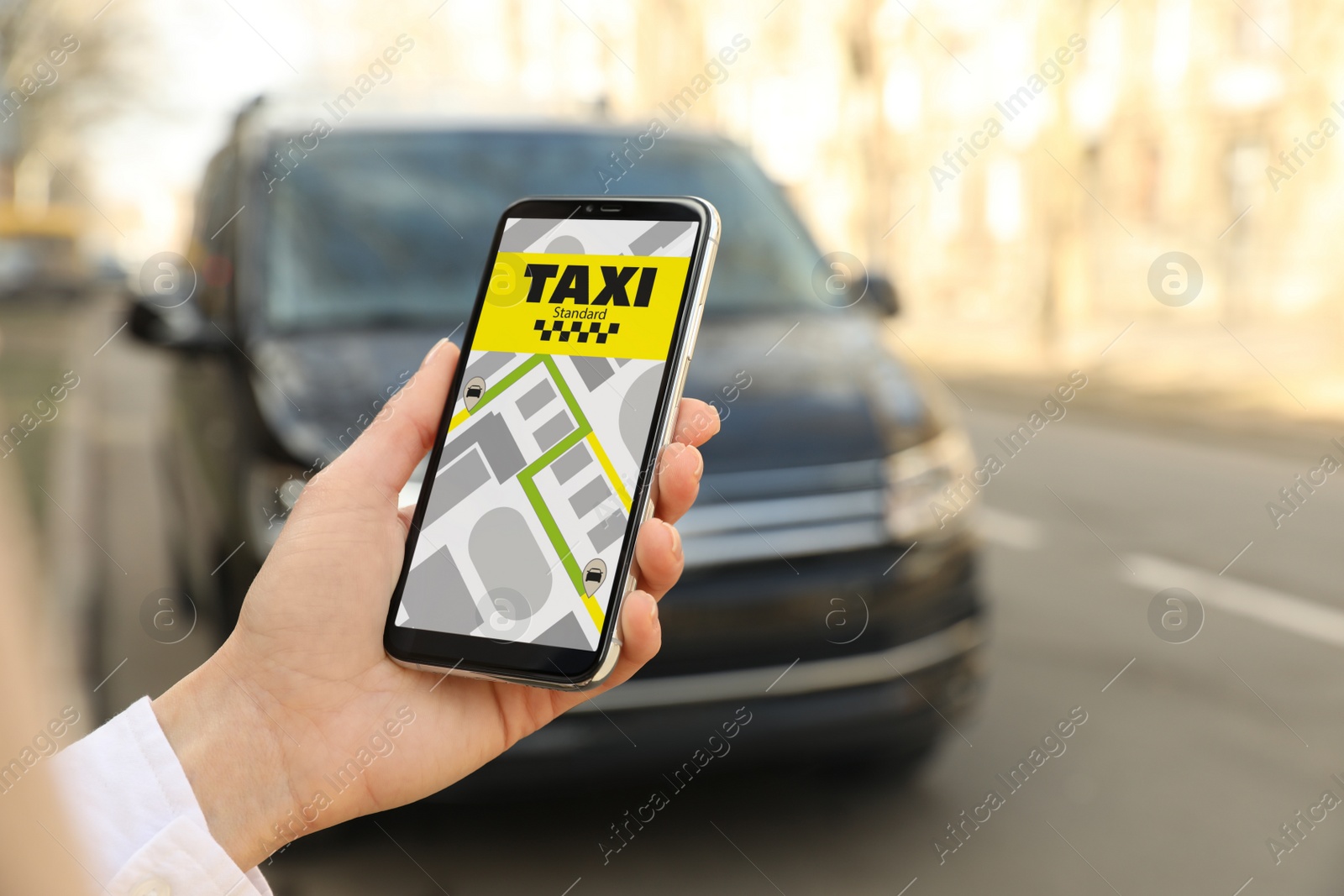 Photo of Woman ordering taxi with smartphone on city street, closeup