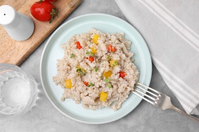 Photo of Delicious barley porridge with vegetables and microgreens on gray table, flat lay