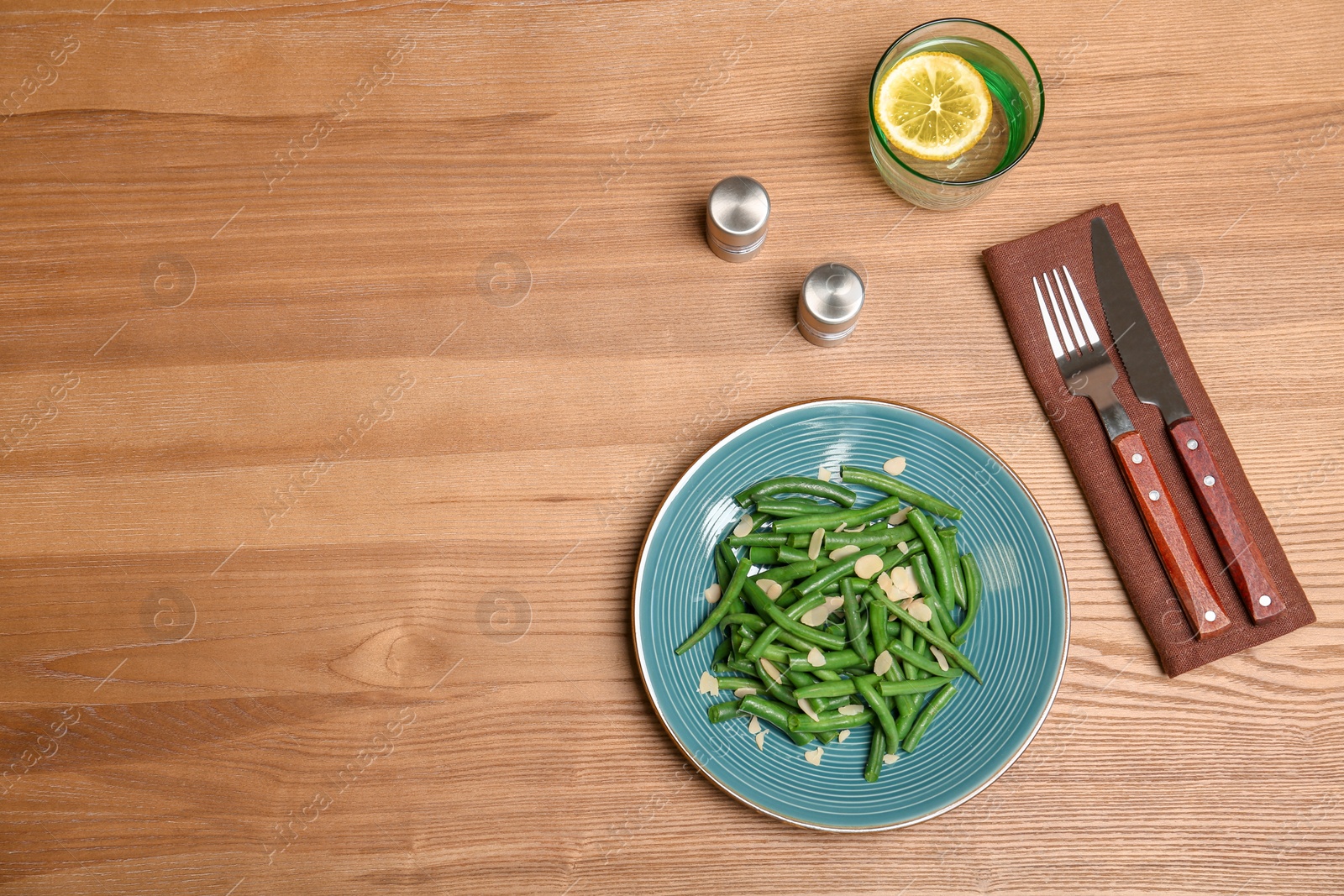 Photo of Plate with tasty green beans and almonds on wooden table, top view