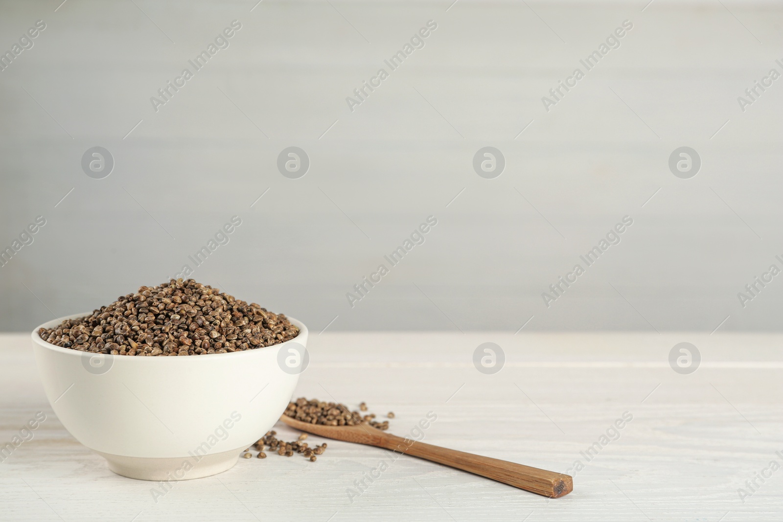 Photo of Ceramic bowl with chia seeds on white wooden table, space for text. Cooking utensils