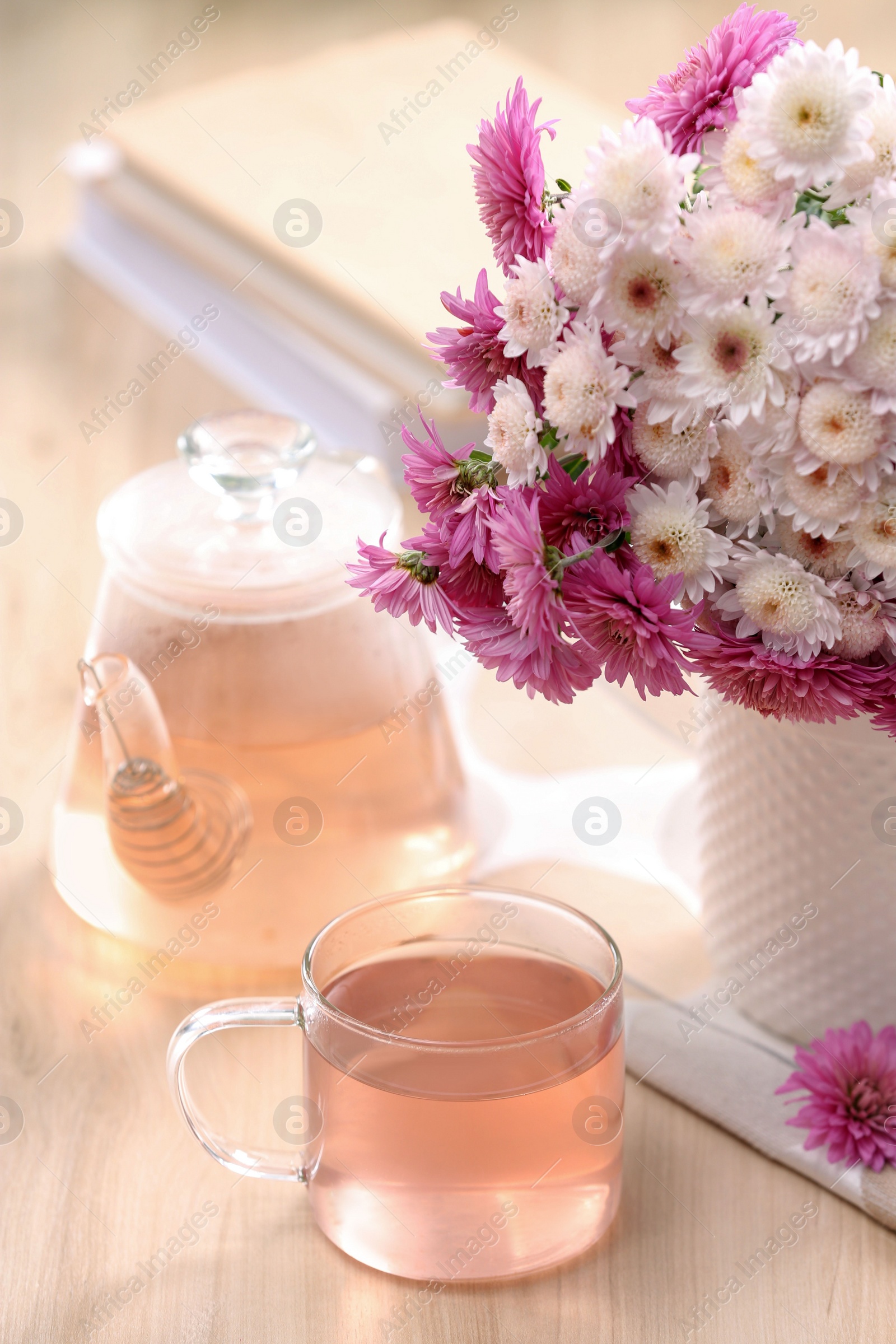 Photo of Fresh delicious herbal tea, books and beautiful bouquet on wooden table