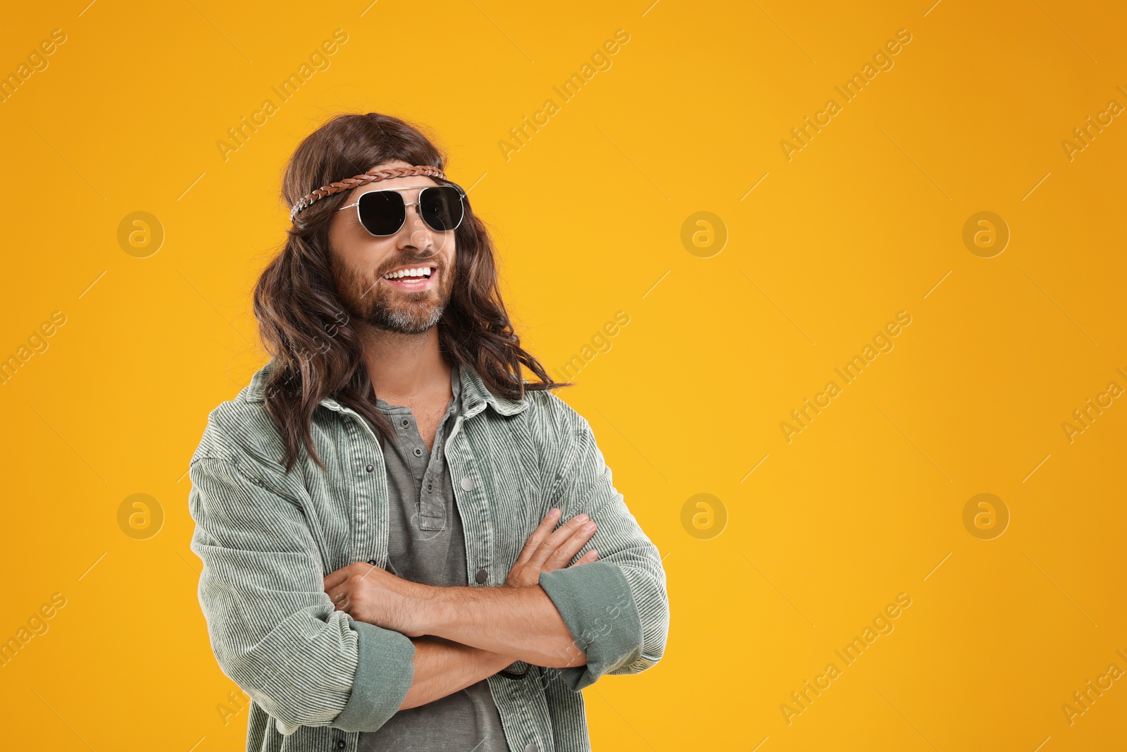 Photo of Stylish hippie man in sunglasses on orange background, space for text