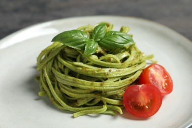 Photo of Tasty tagliatelle with spinach and tomatoes on plate, closeup. Exquisite presentation of pasta dish