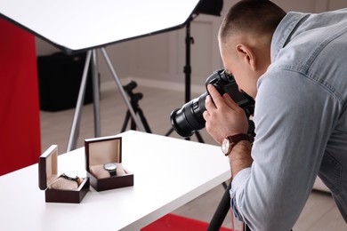 Photo of Professional photographer taking picture of expensive wristwatches in studio