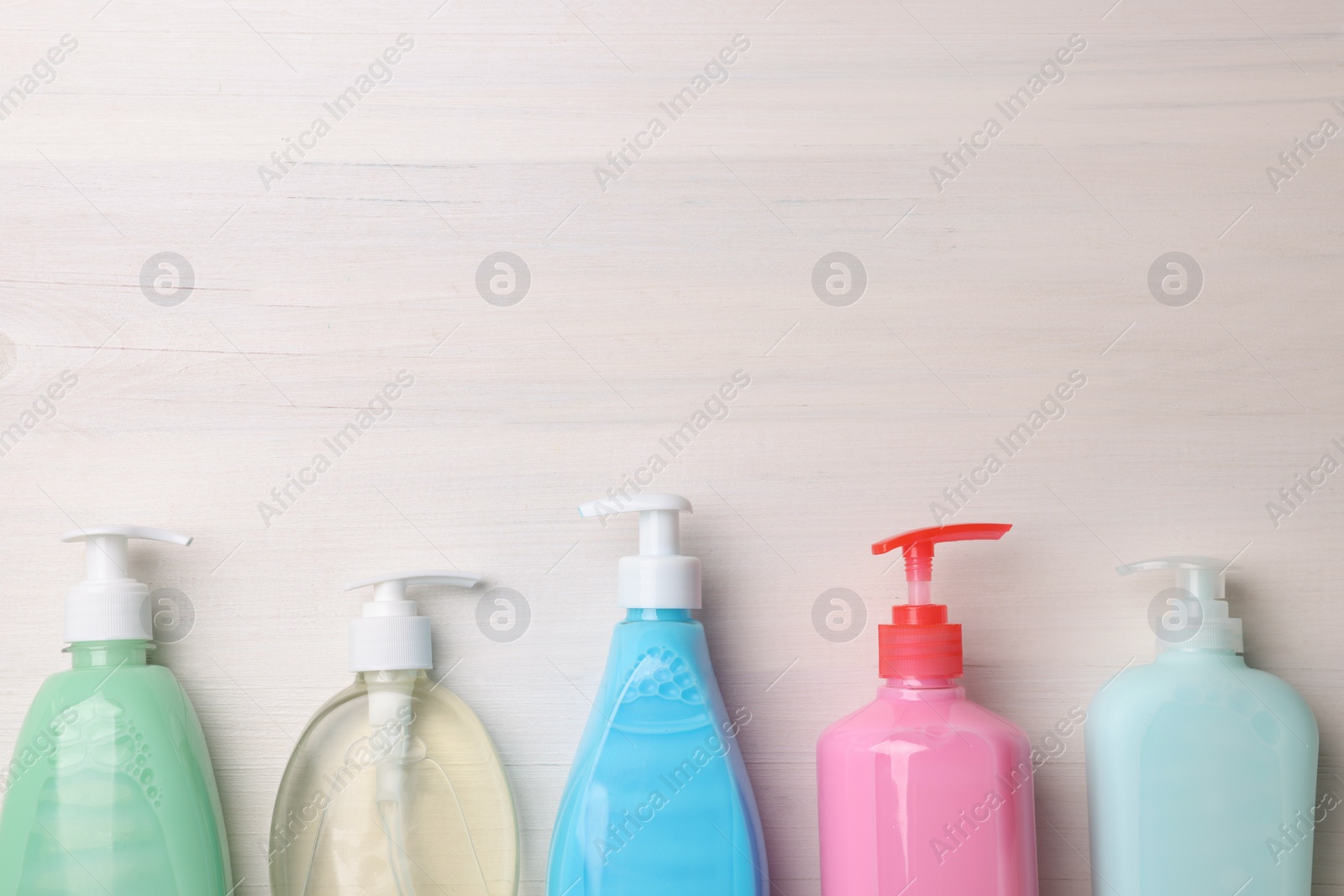 Photo of Many different dispensers of liquid soap on white wooden table, flat lay. Space for text