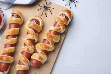 Cute sausage mummies served on white table, flat lay with space for text. Halloween party food