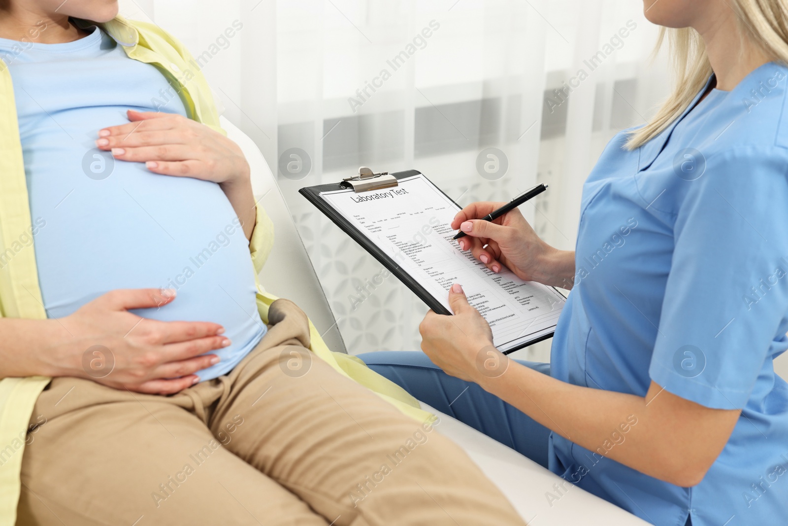 Photo of Doctor with results of laboratory test consulting pregnant patient in clinic, closeup