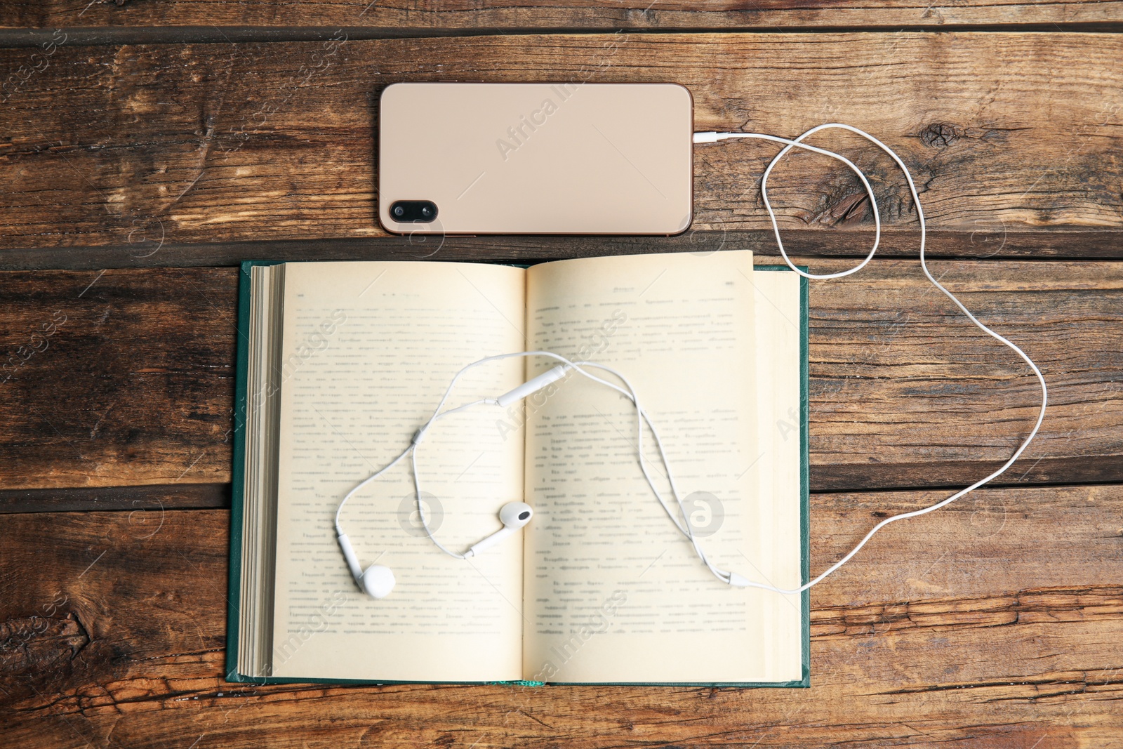 Photo of Book, headphones and smartphone on wooden table, flat lay