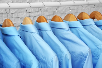 Photo of Rack with clean clothes on hangers after dry-cleaning indoors