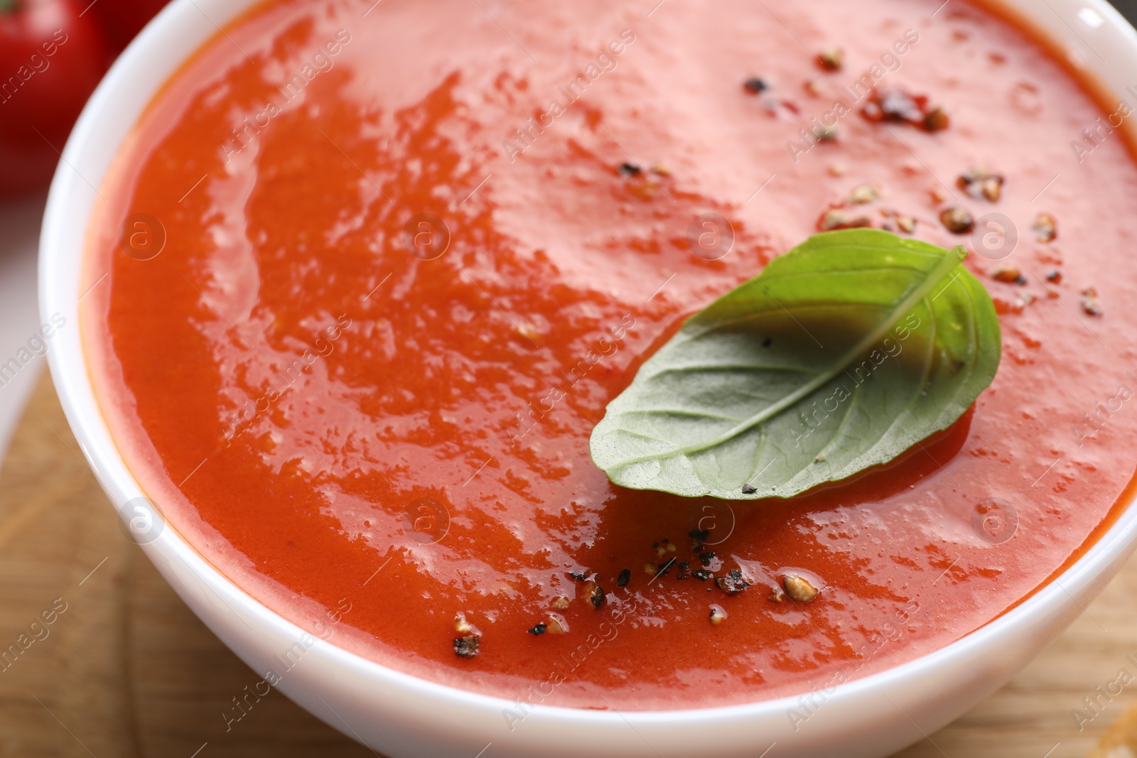 Photo of Delicious tomato soup with basil and spices on table, closeup