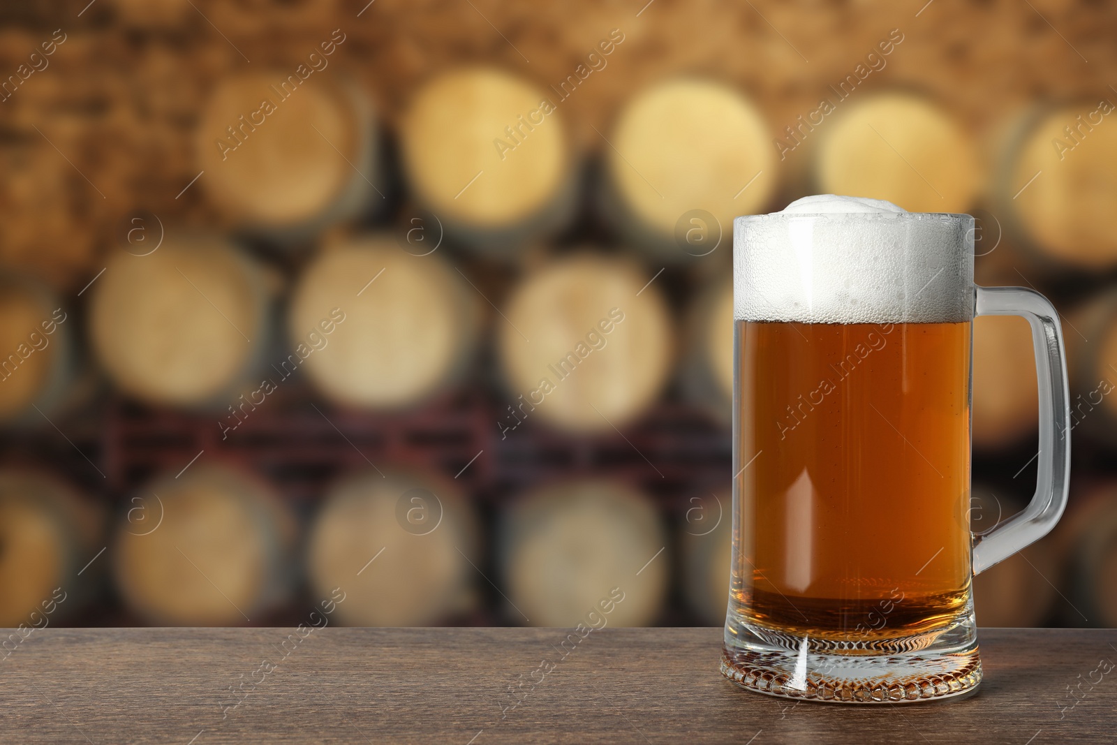 Image of Mug with fresh beer on wooden table in cellar, space for text