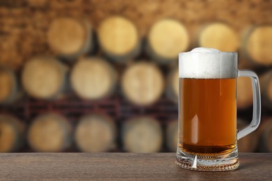 Image of Mug with fresh beer on wooden table in cellar, space for text