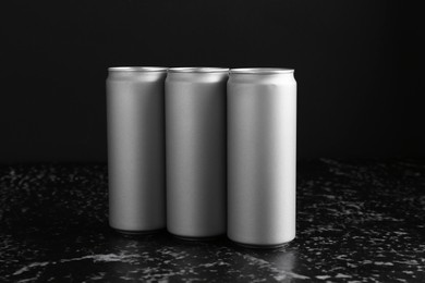 Photo of Energy drinks in cans on black textured table