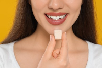 Woman with bubble gum on yellow background, closeup