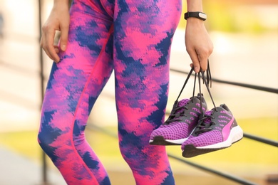 Photo of Young woman with training shoes outdoors, closeup