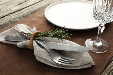 Photo of Stylish setting with cutlery, glass and plate on wooden table, closeup