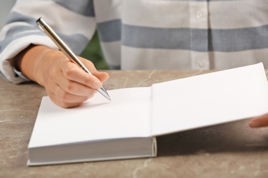 Photo of Writer signing autograph in book at table, closeup