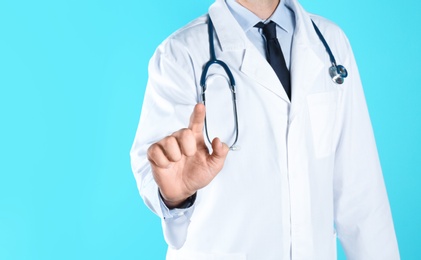 Photo of Male doctor pointing on color background, closeup