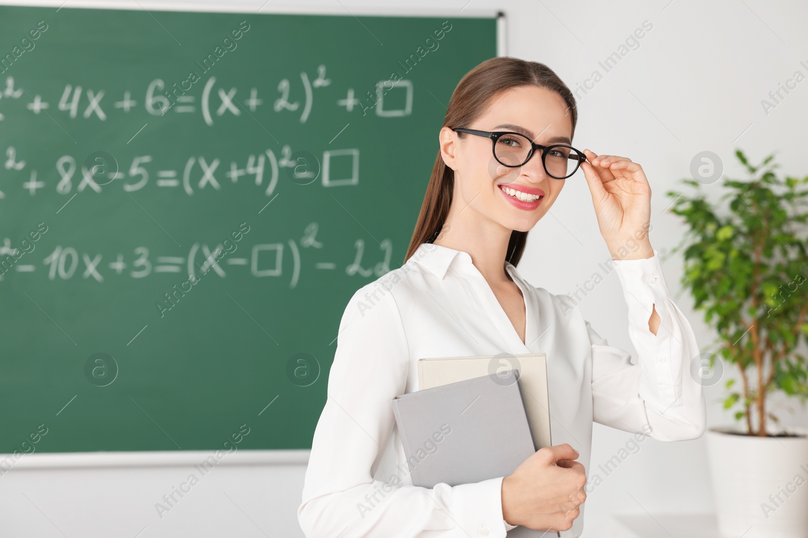 Photo of Portrait of young math’s teacher near chalkboard in classroom