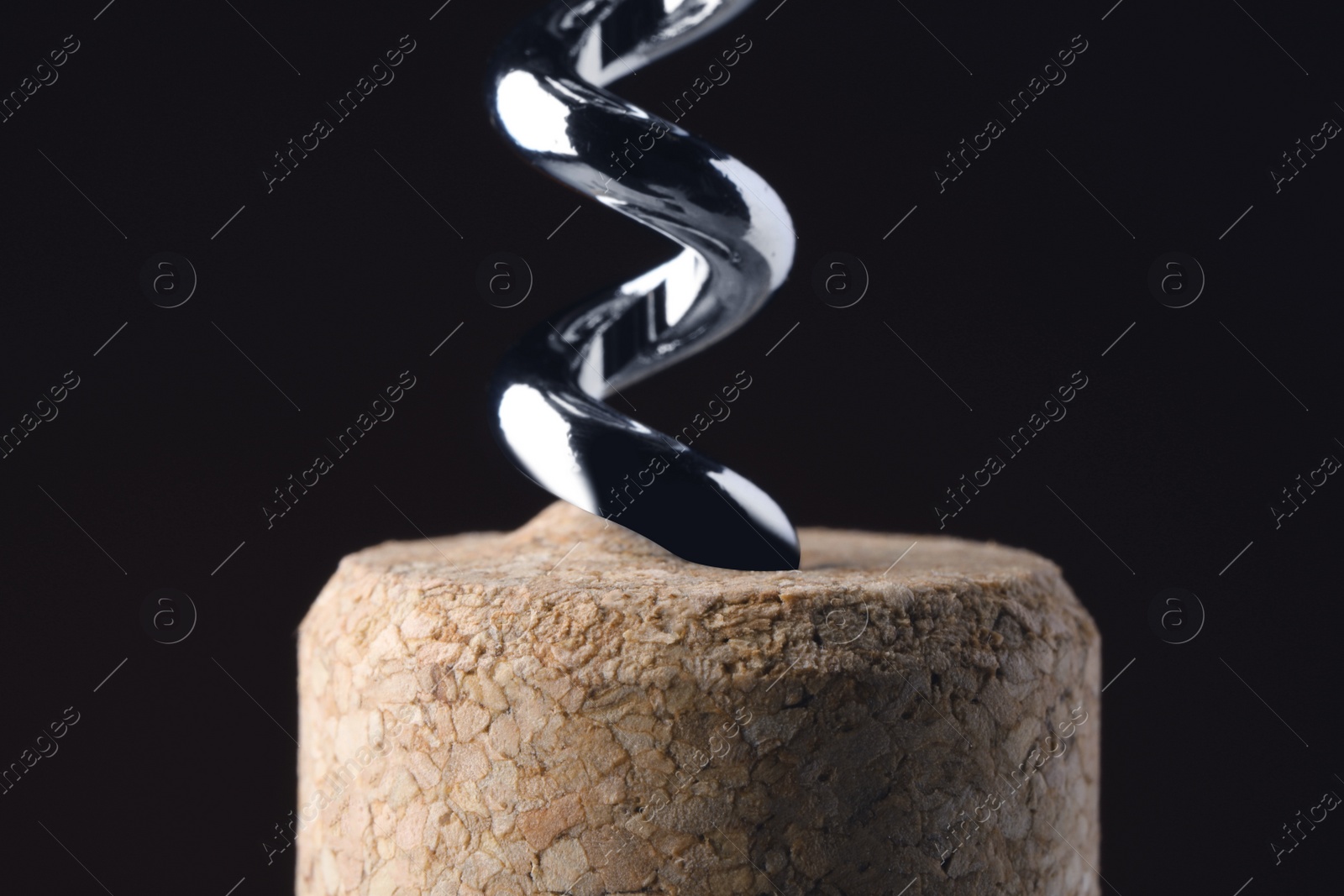 Image of Corkscrew with cork against dark background, closeup