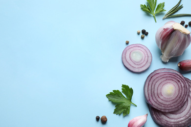 Flat lay composition with onion and spices on light blue background. Space for text