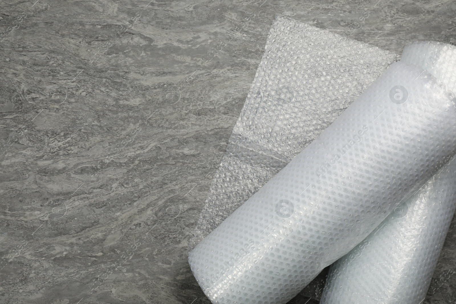 Photo of Bubble wrap rolls on grey background, top view. Space for text